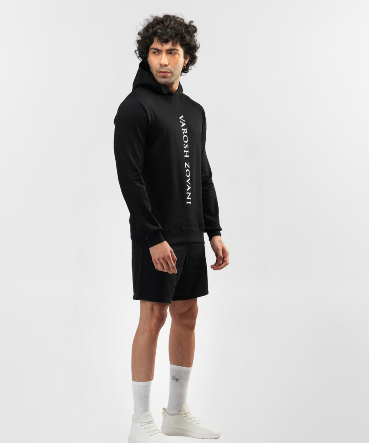 Three-quarter front view of model wearing Falcon black hoodie with black shorts